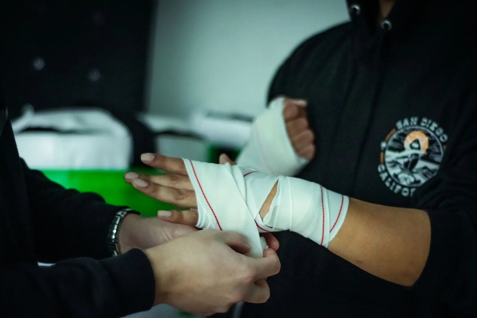 Hands getting wrapped for boxing training in gym setting, focus on preparation.